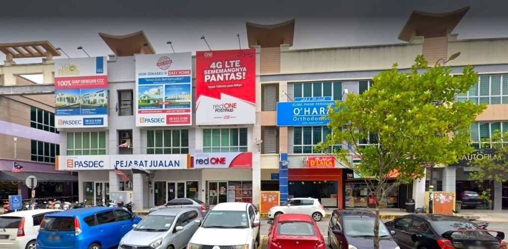 Deretan lot kedai komersial bertingkat di Kuantan, Malaysia. Tumpuan utama ialah redONE Postpaid customer service center dengan etalase merah putih yang menonjol serta sepanduk iklan "4G LTE" yang besar di atasnya. Di sebelah kiri ialah pejabat jualan PASDEC, dan di sebelah kanan ialah O'Hara Orthodontics dan restoran D'Laila