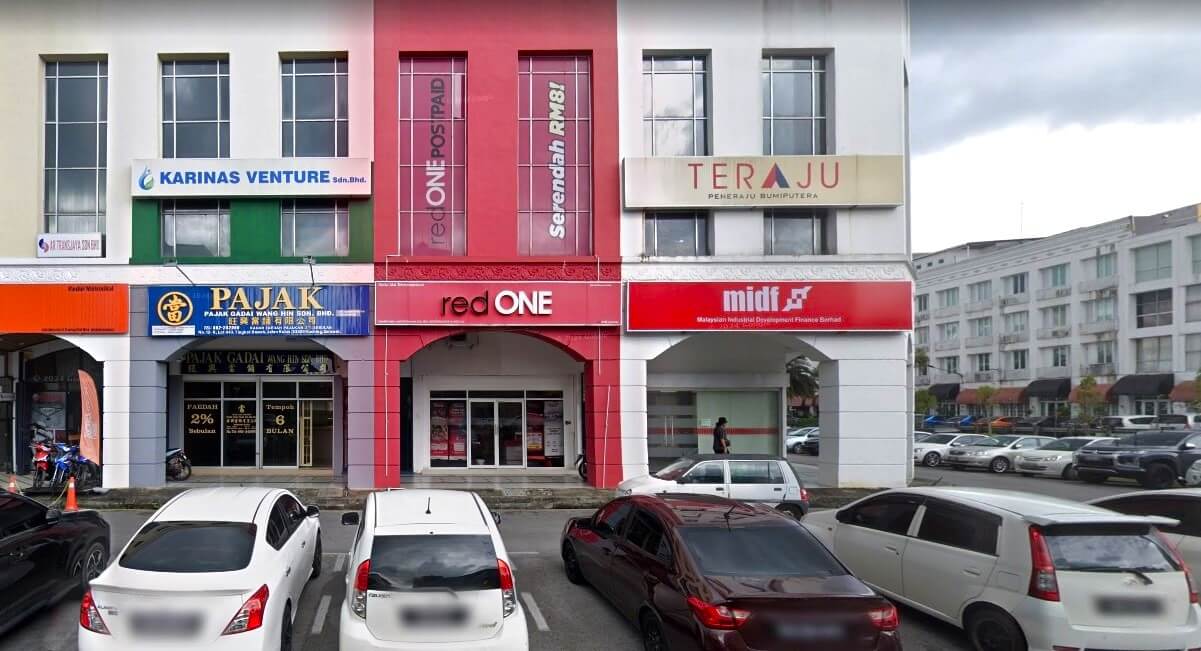 Barisan komersial bertingkat di Kuching, Malaysia, yang menampilkan redONE Customer Service Centre berwarna merah terang sebagai kedai utama. Di sebelah kirinya terdapat papan tanda "Pajak" berwarna biru, dan di sebelah kanannya terdapat pejabat "midf" berwarna merah