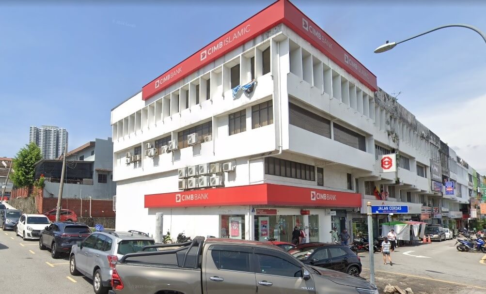 Sebuah bangunan bertingkat CIMB Bank dan cawangan CIMB Islamic di sudut jalan di Taman Connaught, Cheras, yang menampilkan dinding putih, papan tanda korporat merah dan kereta yang diletakkan di sepanjang tepi jalan