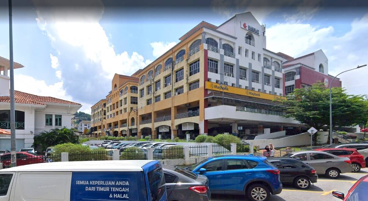 Pemandangan luar bangunan komersial bertingkat di Taman Setiawangsa, yang menampilkan cawangan Maybank di tingkat bawah. Bangunan itu berwarna putih dan kuning dengan tingkap melengkung, terletak di belakang tempat letak kereta yang sibuk dipenuhi dengan pelbagai jenis kereta