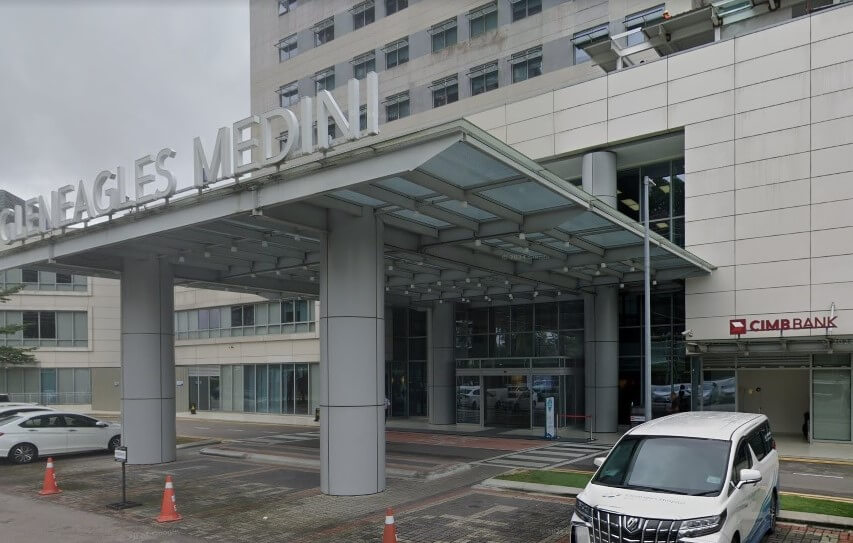 Pintu masuk ke Hospital Gleneagles Medini menampilkan kanopi kaca moden yang besar yang disokong oleh tiang kelabu. Di sebelah kanan pintu masuk utama, cawangan CIMB Bank kelihatan