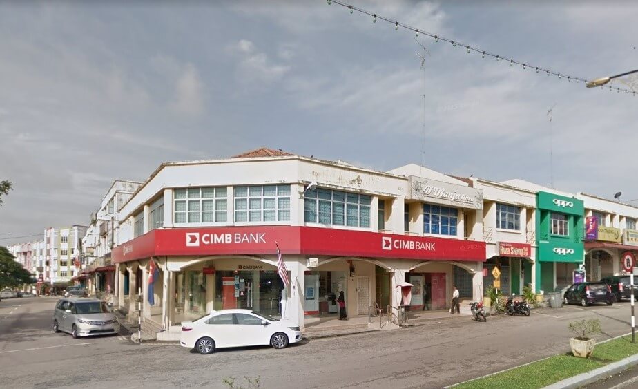Pemandangan sudut lebar, aras jalan di selekoh CIMB Bank di Bukit Gambir, Malaysia. Bangunan dua tingkat ini mempunyai sepanduk merah yang menonjol dengan logo CIMB Bank putih yang melilit selekoh