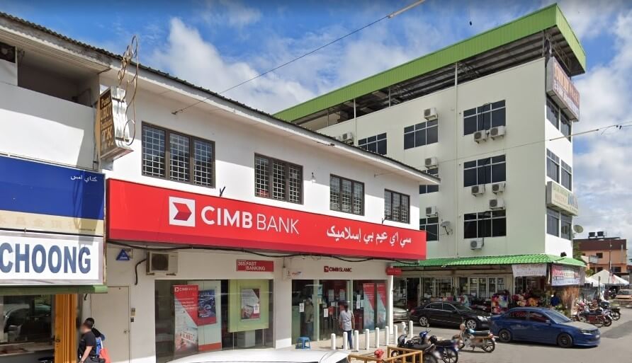 Gambar pemandangan jalan cawangan CIMB Bank Jerantut di Jerantut, Malaysia. Bangunan putih dua tingkat itu mempunyai papan tanda segi empat tepat merah yang menonjol dengan logo dan nama CIMB Bank dalam tulisan Inggeris dan Jawi
