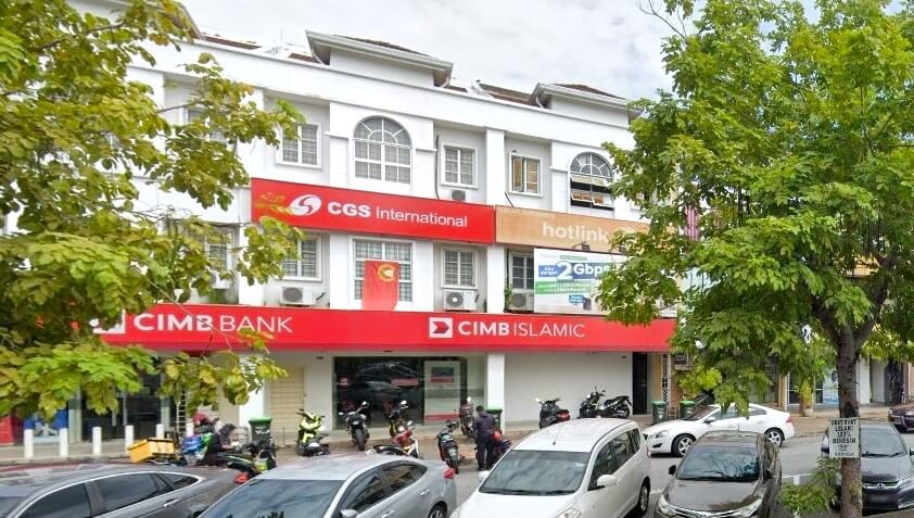 Gambar lebar bangunan komersial putih tiga tingkat yang menampilkan cawangan CIMB Bank dan CIMB Islamic di tingkat bawah dengan papan tanda merah yang menonjol. Di atas tebing, terdapat papan tanda untuk CGS International dan Hotlink