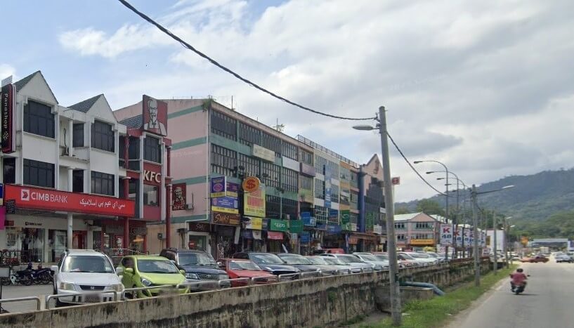 Kawasan komersial di Raub, Malaysia, yang menampilkan cawangan CIMB Bank dan restoran KFC dengan papan tanda merah yang menjadi ciri khasnya. Bangunan bertingkat ini menempatkan pelbagai kedai tempatan, dengan deretan kereta yang diletakkan di hadapan dan jalan berturap di sebelah kanan tempat seorang penunggang motosikal menunggang