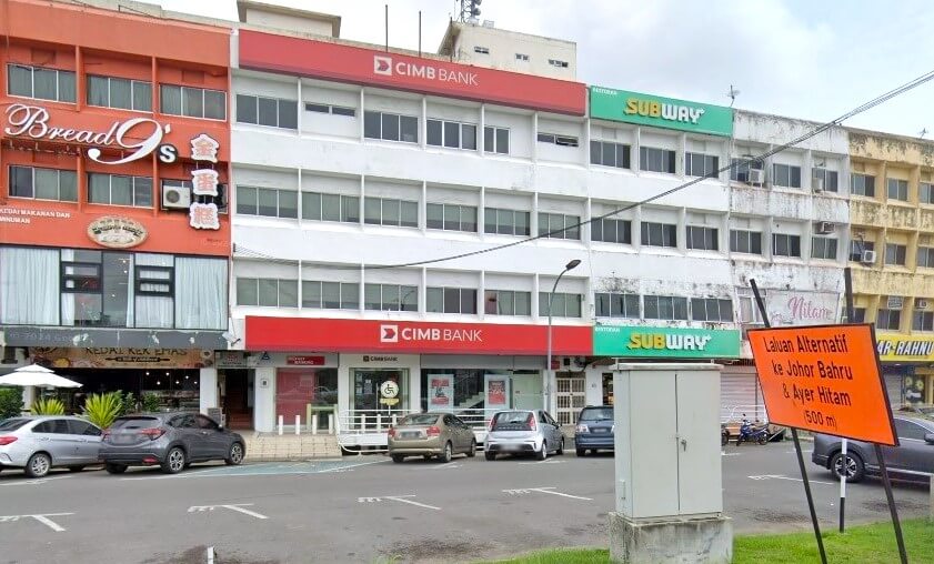 Gambar lebar bangunan komersial bertingkat di Segamat, Malaysia, yang menampilkan cawangan CIMB Bank dan restoran Subway. Di sebelah kiri terdapat sebuah kedai roti bernama Bread 9’s, dan papan tanda jalan berwarna oren di sebelah kanan menunjukkan laluan alternatif ke Johor Bahru dan Ayer Hitam