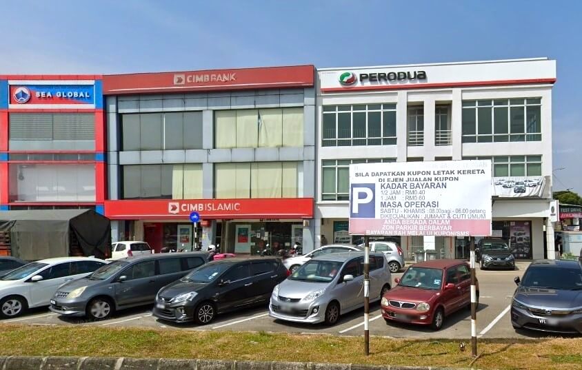 Sebaris bangunan komersial bertingkat di Malaysia, menampilkan cawangan CIMB Bank dan CIMB Islamic (CIMB Bank Taman Nusa Bestari 2) berwarna merah, pengedar kereta Perodua berwarna putih, dan pejabat SEA Global