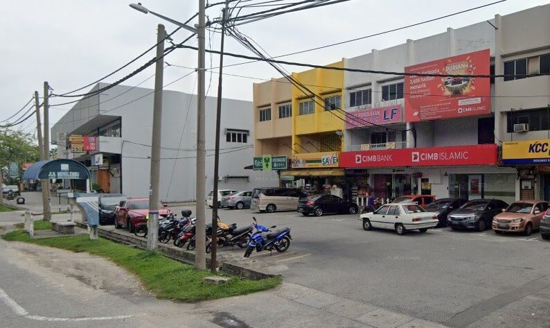 Pemandangan aras jalan CIMB Bank Menglembu yang terletak di deretan rumah kedai komersial bertingkat. Bank ini mempunyai papan tanda merah yang menonjol, dengan kedai "7-Eleven" berwarna hijau dan perniagaan tempatan lain yang kelihatan berdekatan