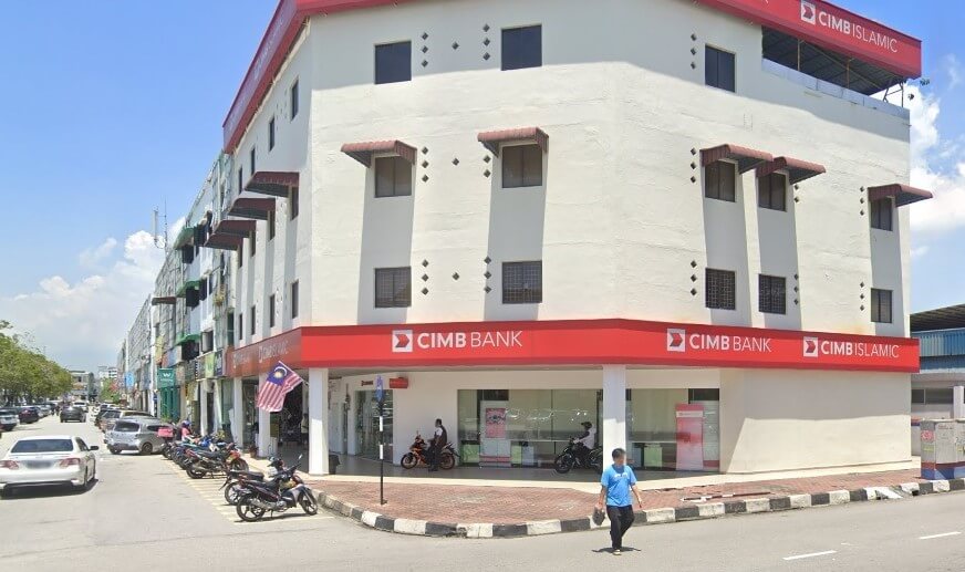Pandangan sudut aras jalan CIMB Bank dan cawangan CIMB Islamic bertingkat di Raja Uda, Butterworth. Bangunan ini mempunyai papan tanda mendatar merah yang menonjol dengan tulisan putih, dinding luar berwarna putih, dan beberapa motosikal diletakkan di sepanjang kaki lima