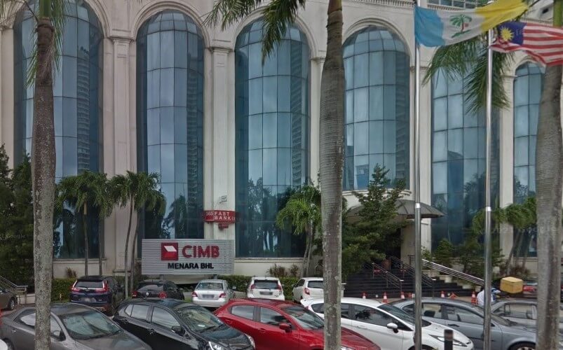 Pemandangan aras jalan CIMB Investment Bank Berhad di Menara BHL di Pulau Pinang, Malaysia. Bangunan ini mempunyai tingkap kaca berwarna biru melengkung yang besar dan papan tanda kelabu yang menonjol dengan logo CIMB merah