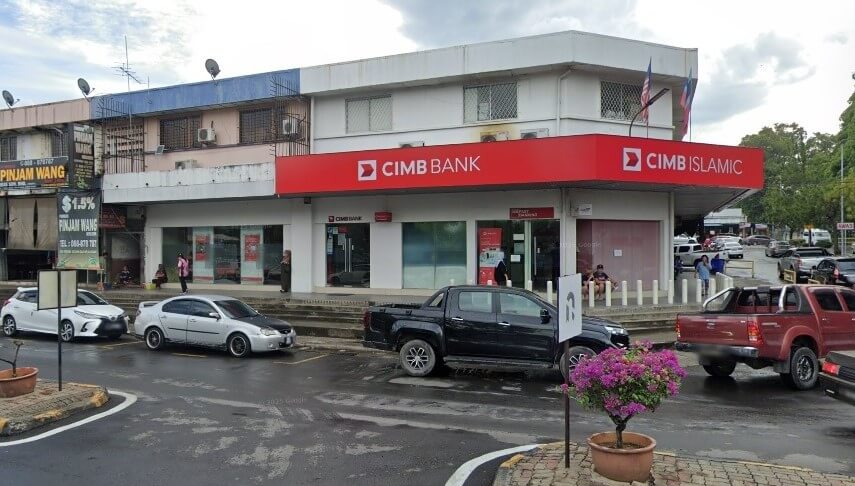 Pemandangan luar lot sudut CIMB Bank dan cawangan CIMB Islamic di Ranau, Malaysia. Bangunan ini mempunyai sepanduk merah yang menonjol dengan tulisan putih di atas kedai kaca
