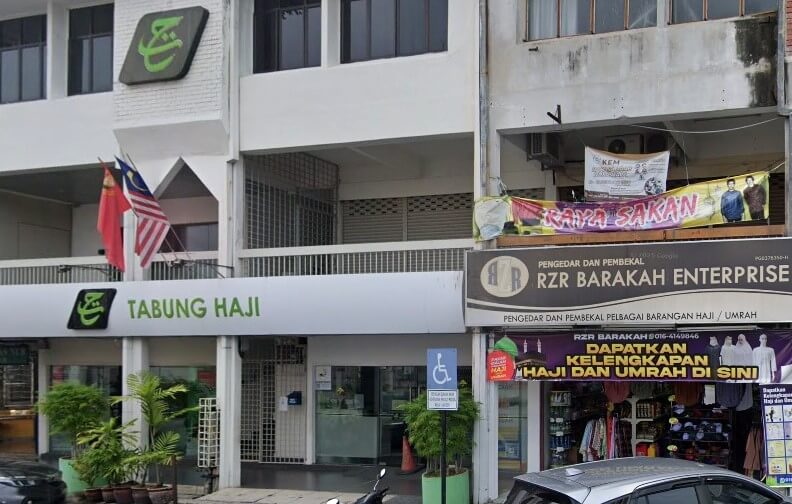 Pemandangan dari lebuh raya cawangan Tabung Haji Kulim. Bangunan bertingkat berwarna putih itu memaparkan logo Tabung Haji hijau dan bendera Malaysia. Di sebelah kanan ialah "RZR Barakah Enterprise," sebuah kedai yang menjual bekalan Haji dan Umrah dengan sepanduk ungu dan patung di tingkap