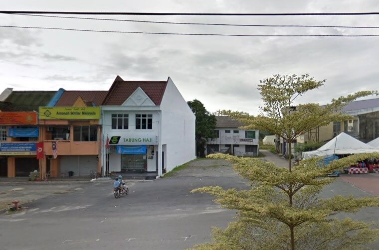 Pemandangan jalan sebuah bangunan dua tingkat berwarna putih di Jeli, Malaysia, yang memaparkan papan tanda hijau "TABUNG HAJI". Di sebelah kirinya terdapat pejabat "Amanah Ikhtiar Malaysia" dengan papan tanda kuning