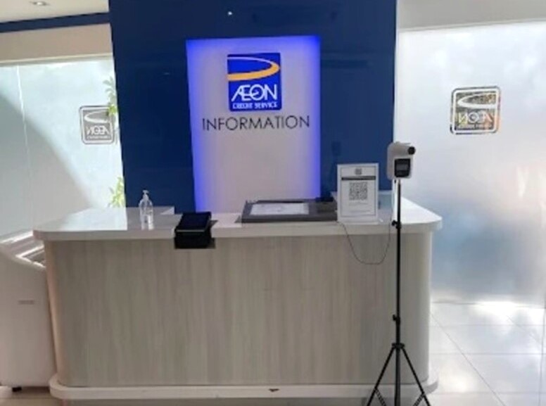 Meja maklumat untuk AEON Credit Kuantan mempunyai papan tanda, pembersih tangan, pengimbas, kod QR dan termometer tanpa sentuh pada tripod