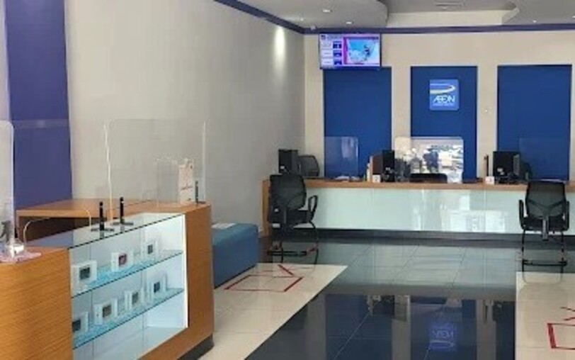 Interior AEON Credit Sungai Petani, menampilkan meja dengan dua stesen kerja, skrin pelindung akrilik, lantai berjubin dengan penanda jarak sosial dan kotak paparan di hadapan