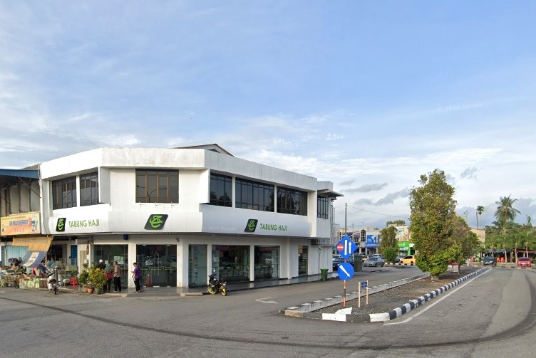 Sebuah bangunan komersial dua tingkat berwarna putih di lot sudut menempatkan pejabat cawangan Tabung Haji Pendang, dengan tingkap besar berwarna gelap dan papan tanda hijau yang memaparkan logo Tabung Haji. Bangunan itu menghadap persimpangan berturap dengan pulau trafik dan papan tanda jalan berwarna biru