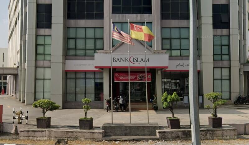 Pintu masuk hadapan cawangan Bank Islam Malaysia Berhad di Klang, Malaysia, memaparkan papan tanda "Bank Islam" merah dan putih, bendera kebangsaan Malaysia, dan bendera negeri Selangor yang berkibar di hadapan