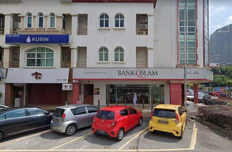 Pandangan luar cawangan Bank Islam Malaysia Berhad di Kota Damansara, yang terletak di bangunan lot kedai bertingkat berwarna putih dengan kereta diletakkan di hadapan