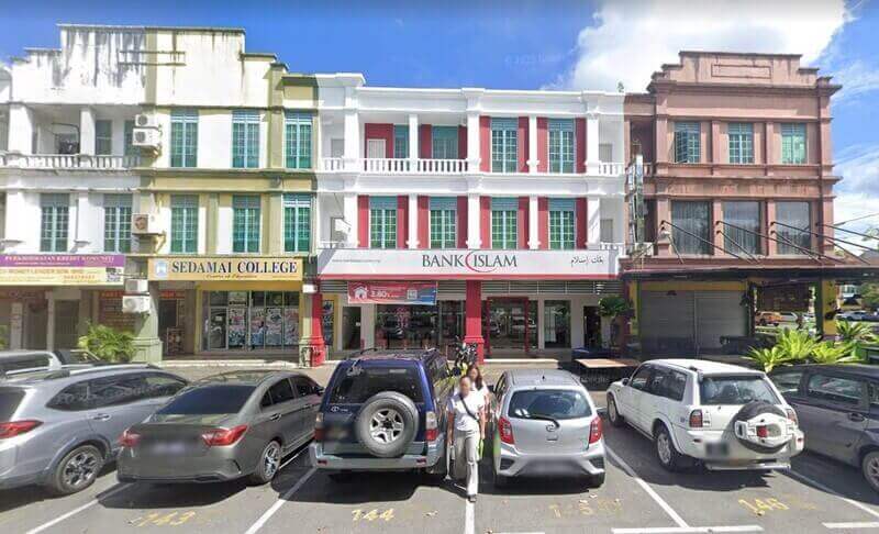 Pemandangan luar Bank Islam Malaysia Berhad cawangan Bintulu, terletak di sebuah rumah kedai putih dan merah bersebelahan Kolej Sedamai dengan kereta-kereta diletakkan di hadapan