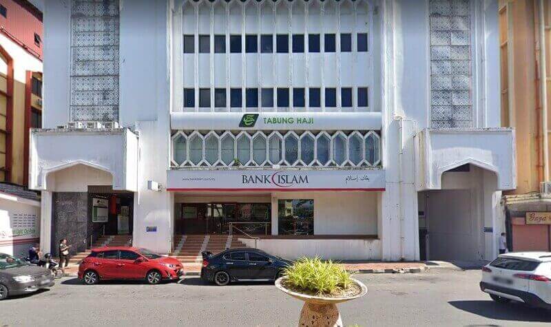 Bahagian hadapan pejabat cawangan Bank Islam dan Tabung Haji di Labuan, menampilkan bangunan bertingkat berwarna putih dengan tempat letak kereta aras jalan