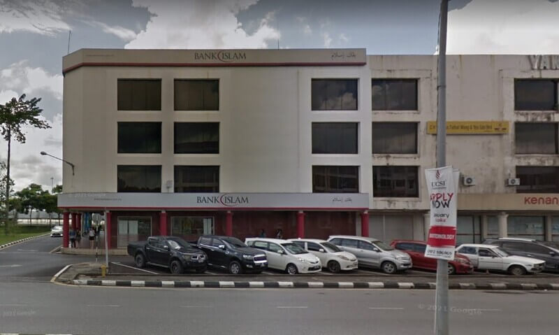 Pandangan luar bangunan Bank Islam Malaysia Berhad cawangan Sibu, menunjukkan papan tanda kedai merah putih, bahagian hadapan tiga tingkat dan kawasan parkir tepi jalan di Sarawak