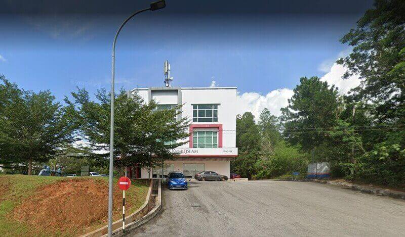 Pemandangan luar bangunan Bank Islam Malaysia Berhad cawangan Jengka di Pahang, menampilkan bahagian hadapan putih dan papan tanda rasmi berlatarbelakangkan pokok dan langit yang cerah