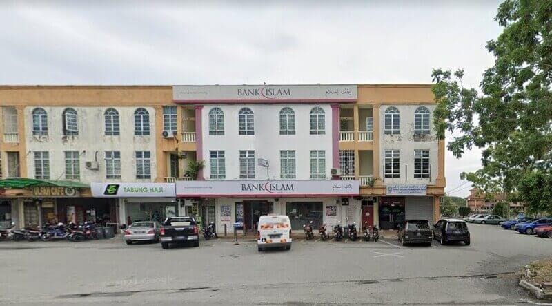 Pemandangan luar cawangan Bank Islam Malaysia Berhad tiga tingkat di Mersing, menampilkan seni bina putih dan perang sawo matang dengan tingkap melengkung. Tingkat bawah merangkumi pintu masuk bank, pejabat Tabung Haji dan kenderaan yang diletakkan di hadapan