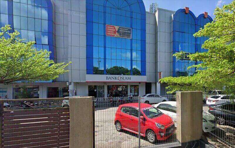Pemandangan luar cawangan Bank Islam Malaysia Berhad di Pasir Gudang, menampilkan bahagian hadapan kaca biru dan sebuah kereta merah yang diletakkan di latar depan