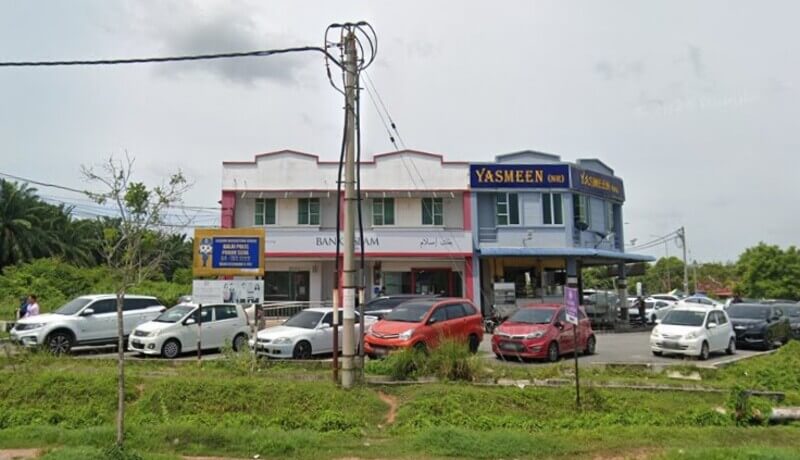 Pandangan luar cawangan Bank Islam Malaysia Berhad di Pokok Sena, yang terletak di bangunan komersial dua tingkat di sebelah bangunan biru dengan papan tanda "Yasmeen", dengan beberapa kereta diletakkan di hadapan