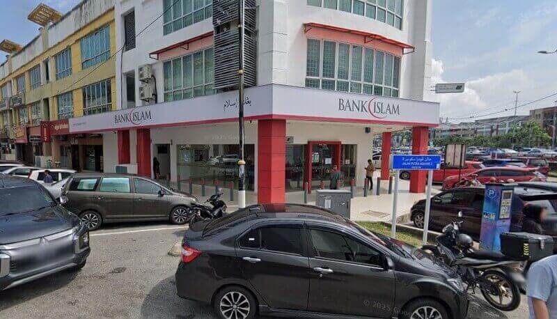 Pandangan luar cawangan Bank Islam di Dataran Putra, menampilkan kedai putih dan merah di sudut jalan dengan kereta yang diletakkan dan papan tanda jalan biru di latar depan