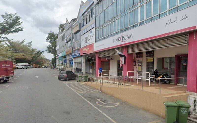 Pandangan luar cawangan Bank Islam Malaysia Berhad di sudut Dataran Putra, menampilkan papan tanda putih dan merah yang menonjol, kedai kaca dan kawasan parkir jalanan yang sibuk di hadapan