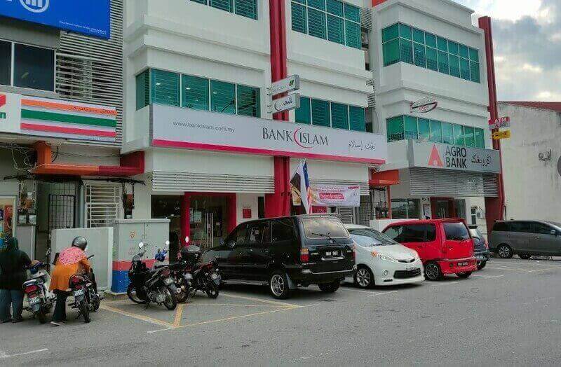Pandangan luar cawangan Bank Islam Malaysia Berhad di Temerloh, memaparkan papan tanda putih dan merah, terletak di sebelah Agro Bank dan 7-Eleven dengan beberapa kereta dan motosikal diletakkan di hadapan