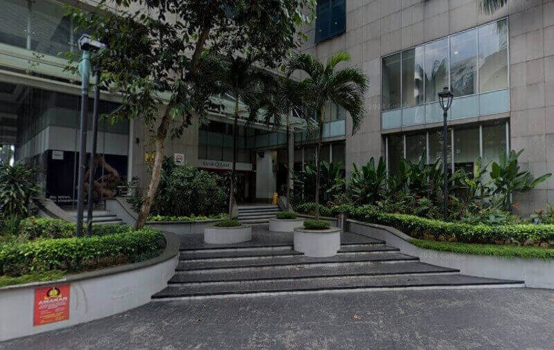 Pemandangan luar cawangan Bank Islam Malaysia Berhad di KL Sentral, menampilkan bahagian hadapan batu moden, tingkap kaca besar dan pintu masuk berlandskap dengan anak tangga bertingkat dan pokok palma