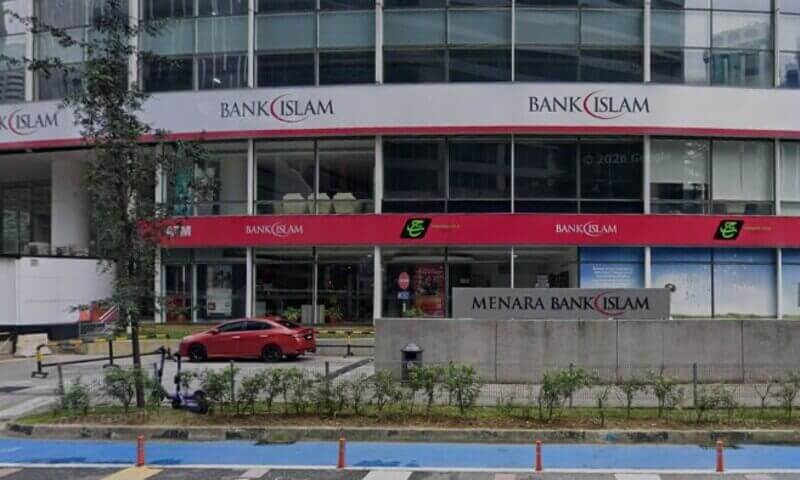 Pandangan hadapan pintu masuk bangunan Menara Bank Islam di Kuala Lumpur, menampilkan penjenamaan korporat merah dan putih, tingkap kaca dan sebuah kereta merah yang diletakkan di hadapan