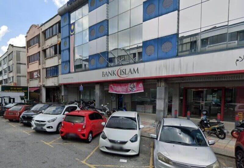 Pandangan luar cawangan Bank Islam Malaysia Berhad di Selayang, Malaysia, memaparkan logo merah dan putihnya di bahagian hadapan kedai dengan beberapa kereta dan motosikal diletakkan di sepanjang jalan di hadapan