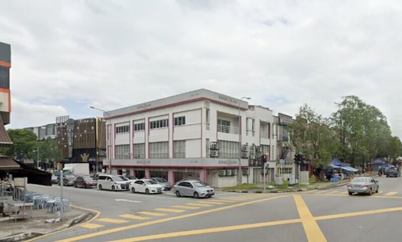 Pemandangan luar cawangan Bank Islam Malaysia Berhad di Seri Petaling, sebuah bangunan sudut tiga tingkat berwarna putih dengan aksen merah, terletak di persimpangan jalan yang sibuk dengan kereta dan lintasan pejalan kaki